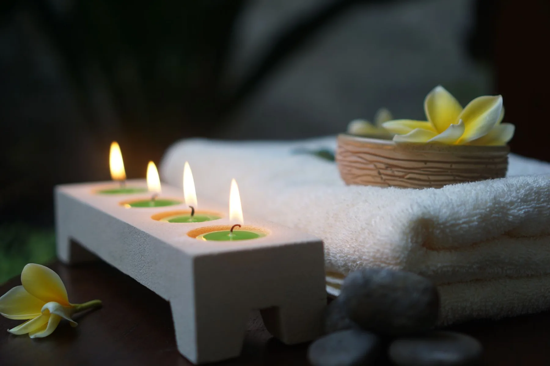 Candles and plumeria flowers on folded spa towels
