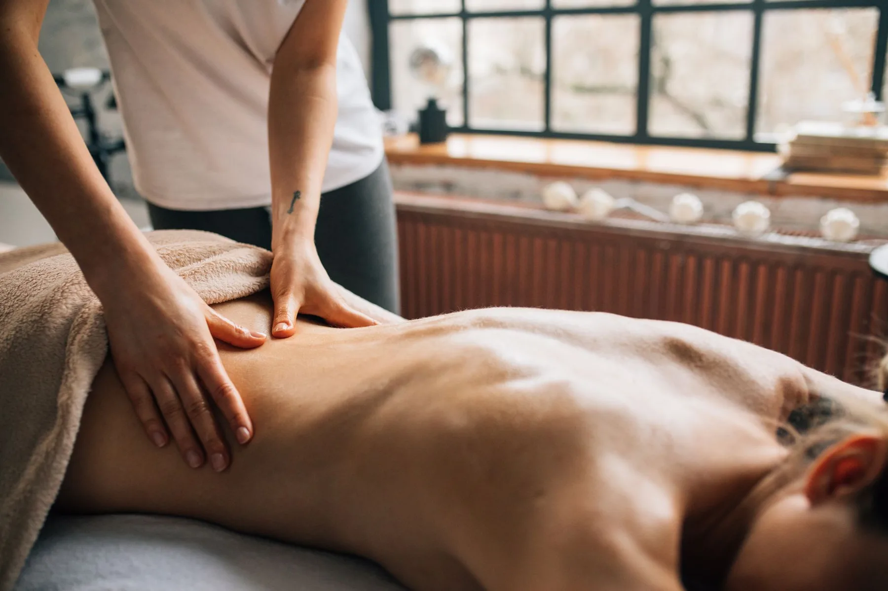 Therapist giving a back massage in a bright treatment room